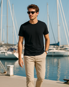 Mann trägt blaues BREDDY’S TENCEL™ T-Shirt und helle BREDDY’S Pants in der Marina