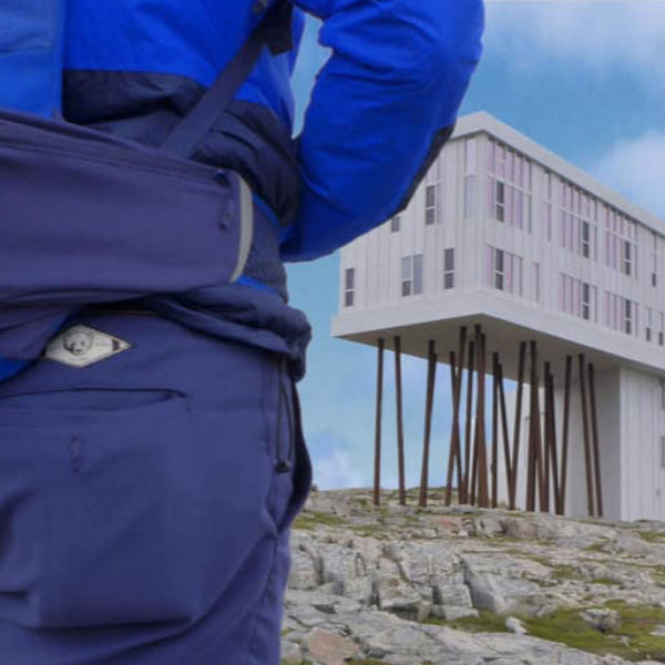 Mann trägt blaue BREDDY’S Pants aus TENCEL™ und steht vor besonderer Architektur