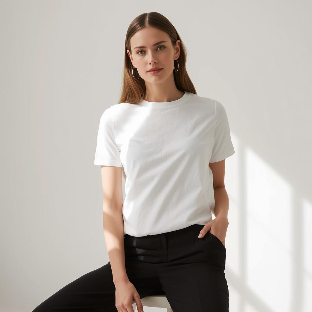 Casual Outfit – Frau im weißen BREDDY’S TENCEL™ T-Shirt auf modernem Hocker.