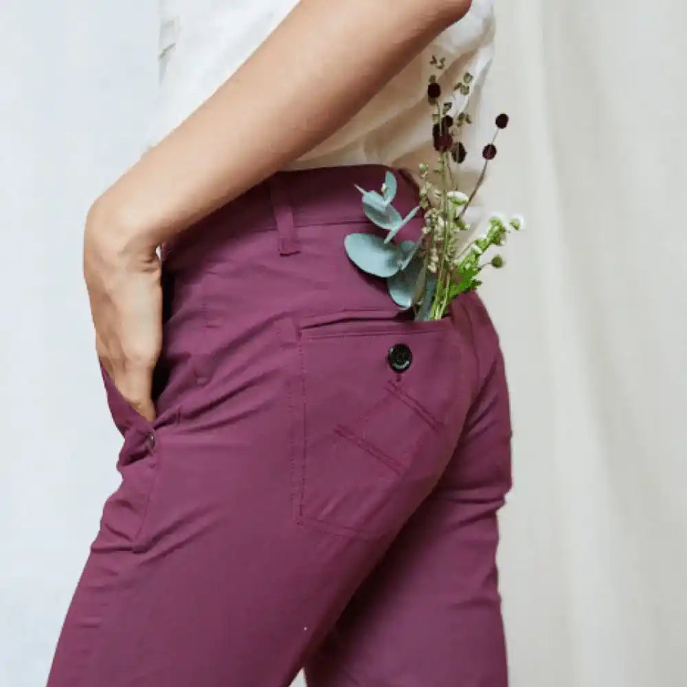 Eine Person in lila Hosen mit Blumen in der Tasche