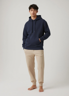 Mann trägt blauen TENCEL™ Hoodie und graue BREDDY’S RELAXED Sweatpants – nachhaltiges, bequemes Outfit aus Europa für Alltag und Freizeit.