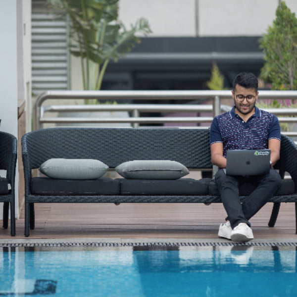 Mann sitzt vor dem Pool mit Laptop auf dem Schoß und trägt schwarze BREDDY’S Pants 